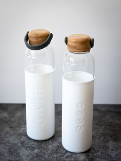 two glass bottles with wooden lids sitting on a table