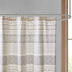 a shower curtain with a white and beige striped pattern on the bottom, hanging in front of a window