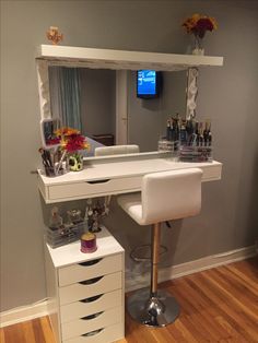 a white desk with drawers and a mirror on it in front of a television set