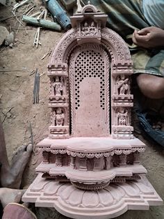 a pink statue sitting on top of a pile of rubble next to a person holding a pair of scissors