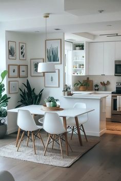 a dining room table with white chairs and pictures on the wall in front of it