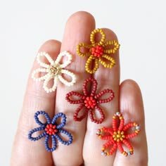 four small beaded flowers are in the palm of someone's hand