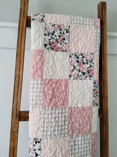 a pink and white quilt hanging from a wooden ladder