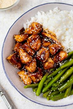 a plate with chicken, rice and green beans on it next to silver utensils