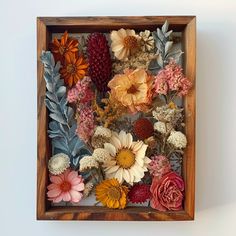 an arrangement of flowers in a wooden frame