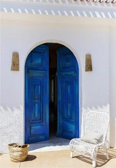 an open blue door to a white building with a wicker basket on the floor