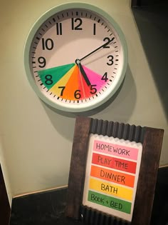 a clock that is on the side of a wall next to a sign reading home work play time dinner bath book bed