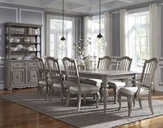 a dining room table and chairs in front of a large window with white trimmings