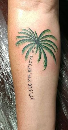 a small palm tree tattoo on the left leg with words written in cursive font