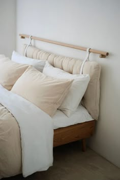 a bed with white sheets and pillows on top of it next to a wooden headboard