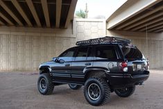 a black suv parked under a bridge with its roof rack mounted on it's back