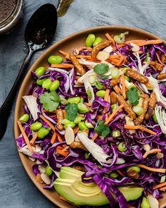 a salad with cabbage, carrots, peas and avocado on a plate