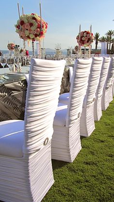 rows of white chairs sitting on top of a grass covered field next to each other