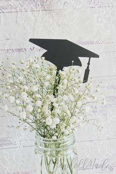 a mason jar filled with flowers and a graduation cap cutout on the top of it