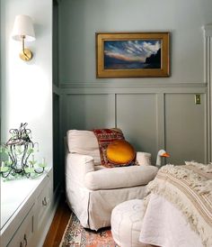 a white chair and ottoman in a room with a painting on the wall above it