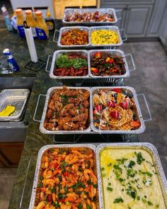 several trays of food are lined up on a counter top, ready to be served