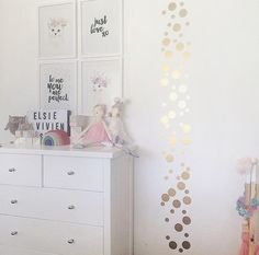 a white dresser sitting in a bedroom next to a wall with gold circles on it