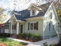 a green house with white trim and brown shutters