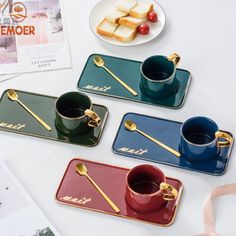 four different colored coffee cups and spoons on a table