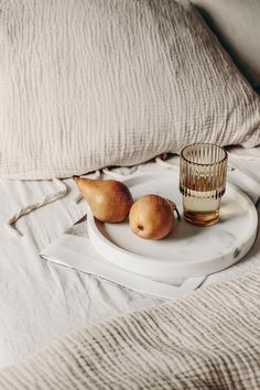 two pears and a glass on a tray in the middle of a bed stock images