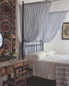 a bed sitting next to a wooden table under a mirror on top of a wall