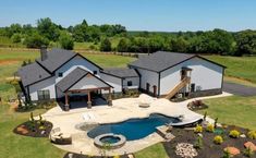 an aerial view of a large house with a pool in the front yard and landscaping around it