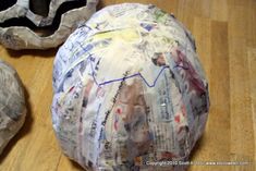 a ball covered in newspaper sitting on top of a wooden floor next to an egg shell