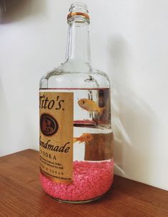 a bottle filled with pink sand sitting on top of a wooden table