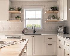 a kitchen filled with lots of white cabinets and counter top space next to a window