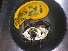 a black plate topped with food on top of a wooden table