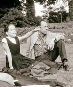 an old black and white photo of a woman combing a man's hair