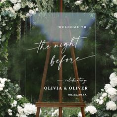 an easel with white flowers and greenery is the welcome sign for this wedding