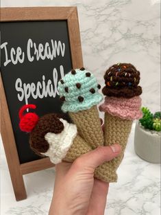 three crocheted ice cream cones are in front of a chalkboard with the words ice cream special written on it