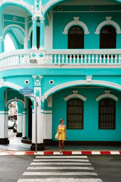 a woman standing in front of a blue and white building