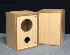 two wooden speakers sitting next to each other on a gray surface in front of a black background