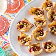 small desserts are arranged on a plate next to wine glasses and plates with utensils