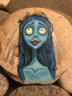 a painted rock with a woman's face on it, surrounded by large rocks