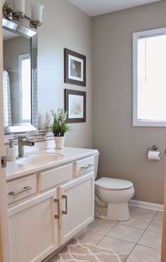 a bathroom with a sink, toilet and pictures on the wall above it's mirror