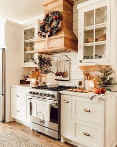 a kitchen with white cabinets and christmas wreath on the stove top above it's burner