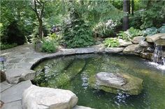 an outdoor pond surrounded by rocks and trees