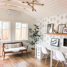 a living room with white furniture and wallpaper on the walls, along with a wooden floor