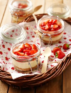 three jars filled with strawberries sitting on top of a table next to spoons