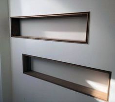 two empty wooden shelves on the wall in a room with white walls and wood trim