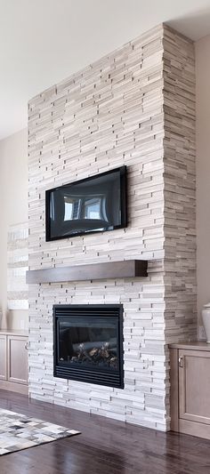 a living room with a tv mounted on the wall and a fire place in front of it