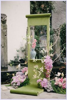 a green stand with flowers and a vase on it