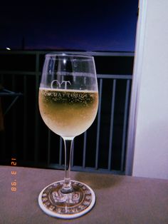 a glass of wine sitting on top of a wooden table next to a window sill