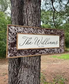 a sign that reads the williamss hanging on a tree in front of some grass