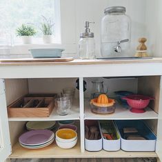 the kitchen cabinet is filled with dishes and bowls