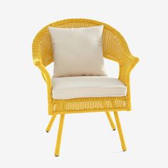 a yellow wicker chair with a white pillow on it's back and side