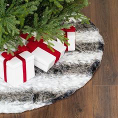 presents are wrapped in red and white paper on a round rug next to a christmas tree